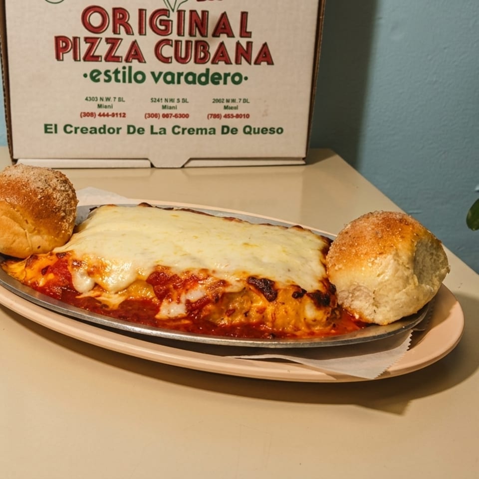 Baked lasagna with melted cheese and two bread rolls, next to an Original Pizza Cubana box.