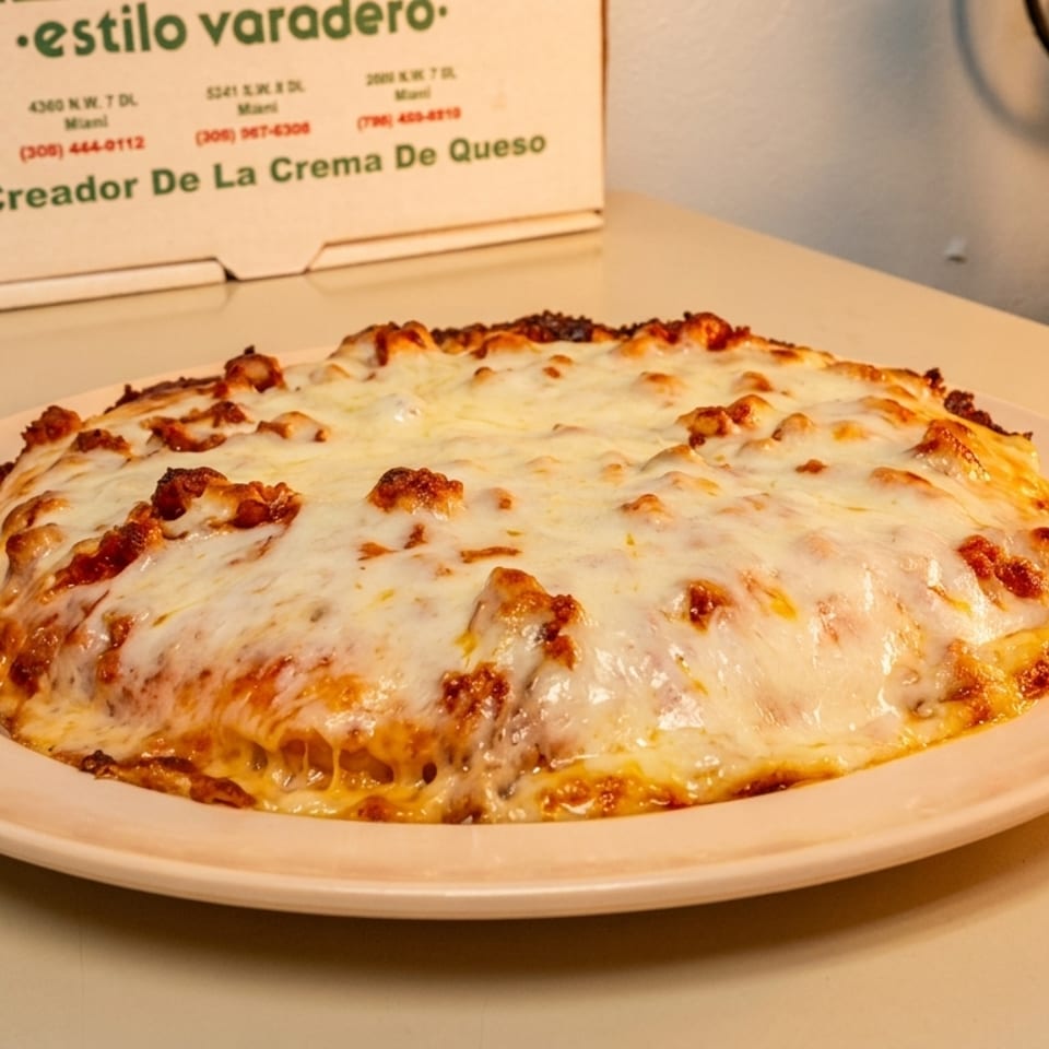 A cheesy, baked dish, possibly lasagna or a casserole, on a light pink plate with a pizza box in the background.